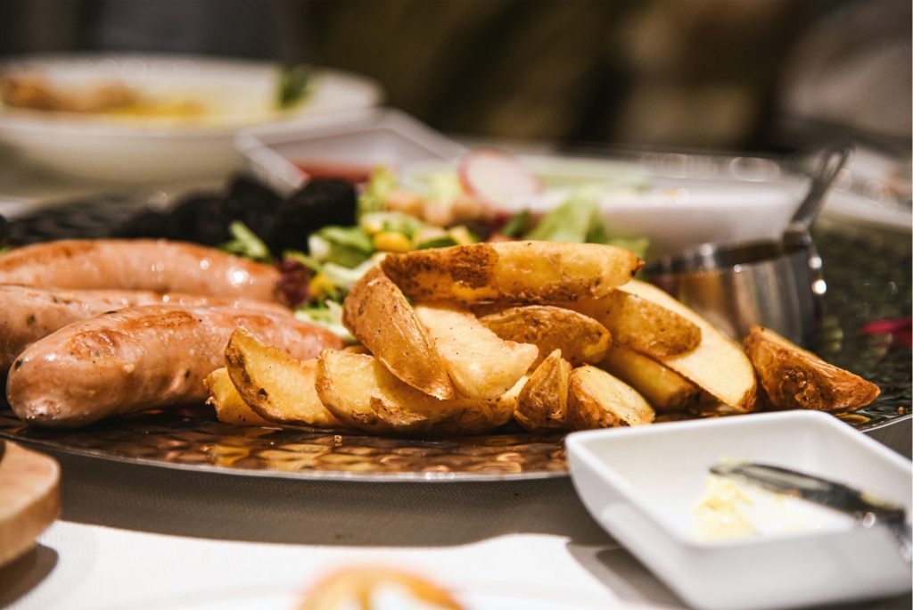 a plate of food with sausages, potatoes and salad